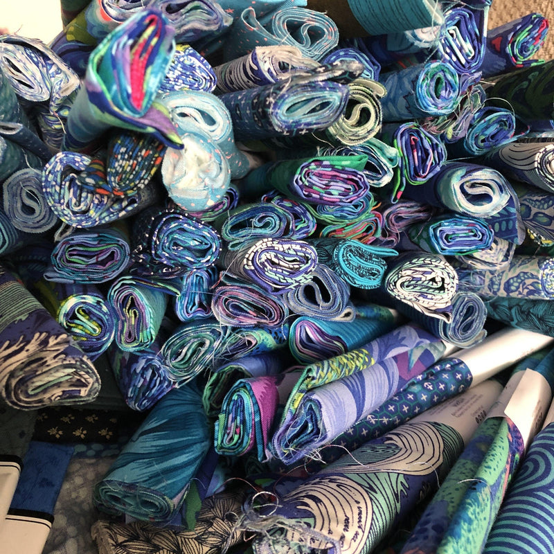 Photo: ends of a pile of blue fabrics rolled up